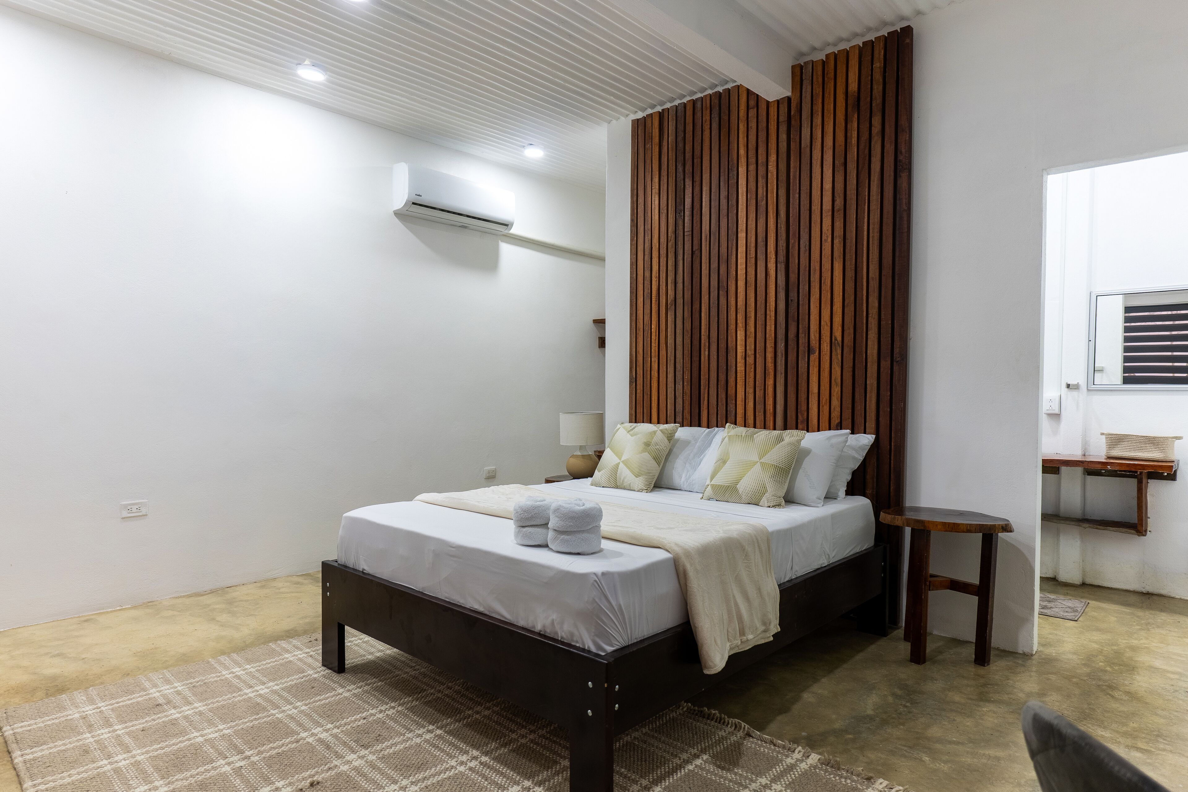 A modern bedroom with a bed, bedside table, and a wooden accent wall.