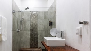 A modern bathroom with a shower, a sink, and a wooden bench. - El Deseo Serendipity Hotel (Colorado)