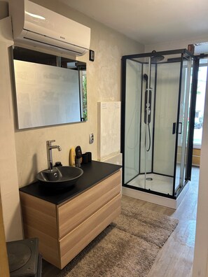 A modern bathroom with a built-in sink, a mirror, a glass-enclosed shower, and a towel rack. - APARTMENT GAL (Novo mesto)