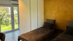 A bedroom with two beds, a sliding glass door to a balcony, and a small table.