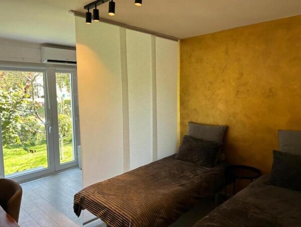 A bedroom with two beds, a sliding glass door to a balcony, and a small table. - APARTMENT GAL (Novo mesto)