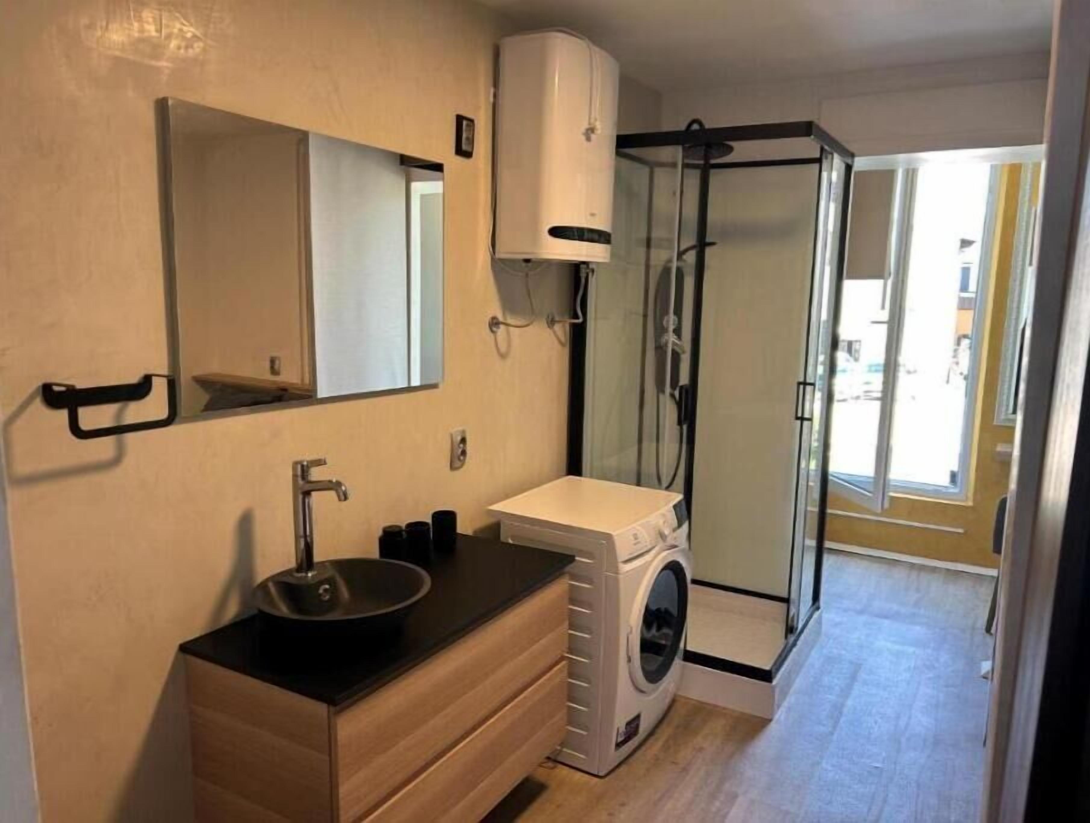 Ein kleines Badezimmer mit Waschbecken, Spiegel und einer Duschkabine aus Glas.