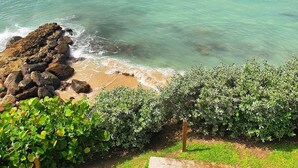A coastal view with clear turquoise waters, a rocky shoreline, and lush greenery. - Merci Buccoo (Scarborough)