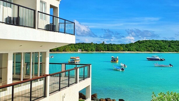 A modern two-story building with a balcony overlooking turquoise waters. - Merci Buccoo (Scarborough)