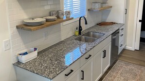 A modern kitchen with white cabinets, granite countertops, and built-in shelves.