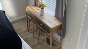 A small, neatly arranged room with a wooden desk, a chair, and a potted plant.