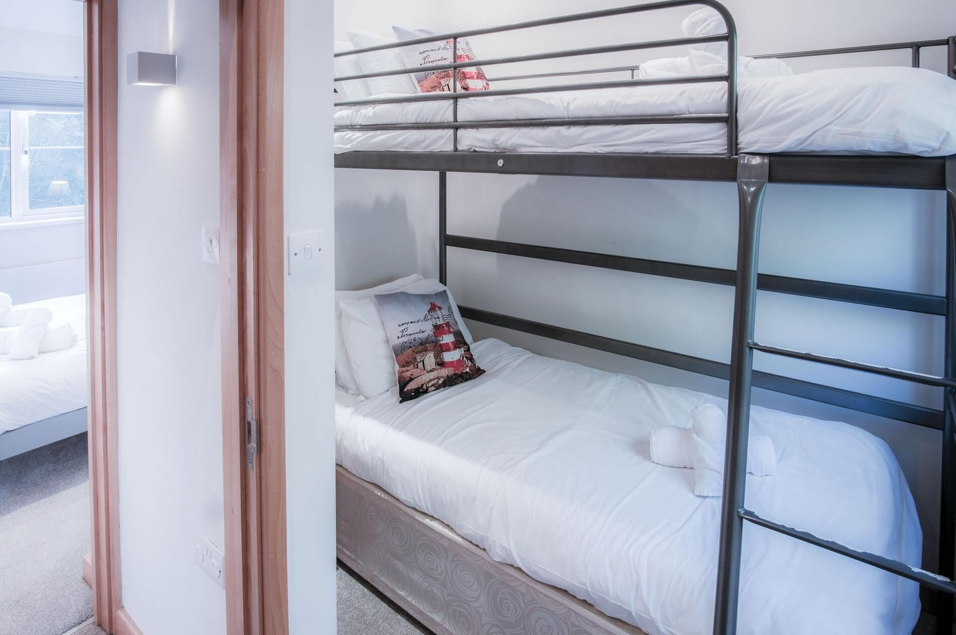 Una cama litera con ropa de cama blanca y una almohada decorativa.