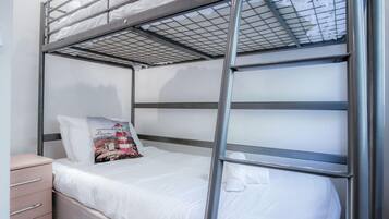 A bunk bed with a metal frame, white bedding, and a decorative pillow.