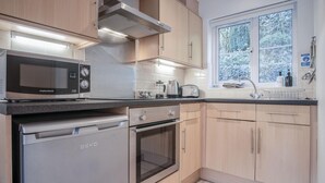 Eine moderne Küche mit integriertem Mikrowellenherd, einer Kaffeemaschine, einem Toaster und einem Spülbecken mit Fenster darüber.