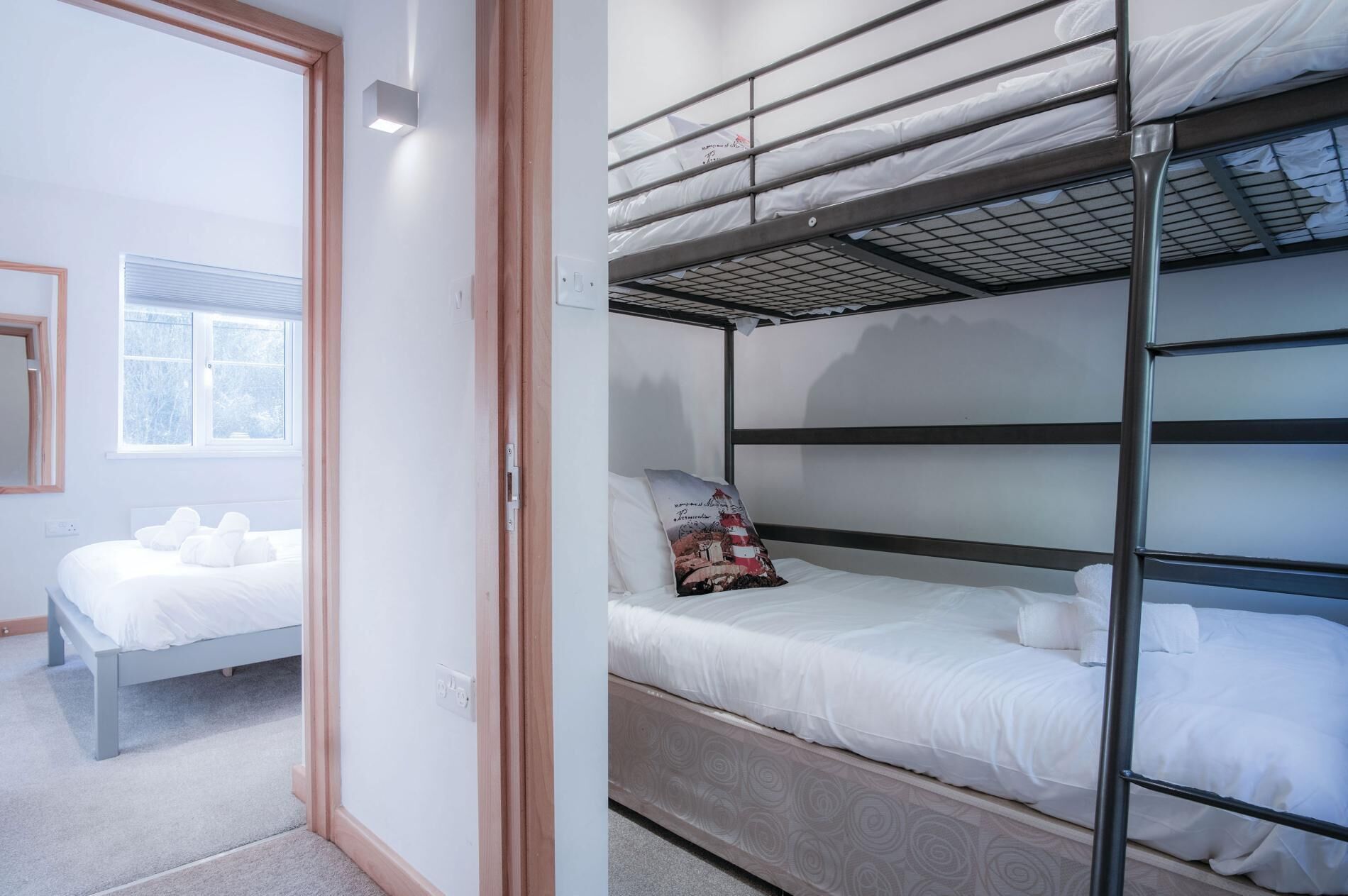 A room with a bunk bed, a single bed, and a window with blinds.