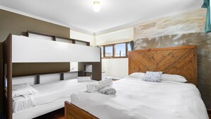A hotel room with bunk beds, a large bed, and a view of the sea. - Price on the Beach 2c Pet-Friendly Steps to Beach (Torquay)