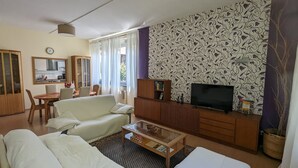 Ett vardagsrum med en soffa, ett soffbord, en tv och en vägg med ett mönster.