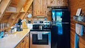 Una cocina compacta con armarios de madera, un refrigerador de acero inoxidable y un horno empotrado.