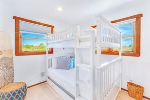 Une chambre avec des lits superposés offrant une vue sur la verdure par les fenêtres.