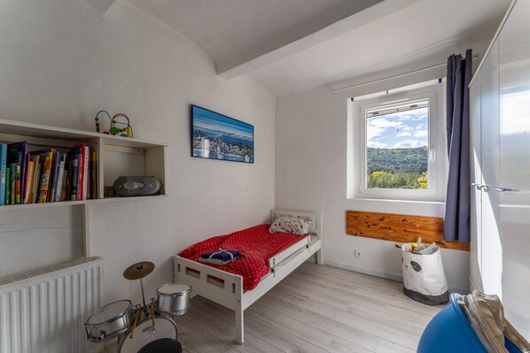 A bedroom with a bed, a bookshelf, a window, and a radiator.