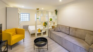 Una sala de estar moderna con un sillón amarillo, un sofá gris, un estante blanco y una mesa de centro negra.
