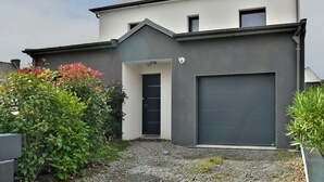 Ein modernes, zweistöckiges Haus mit dunkelgrauer Fassade, einer schwarzen Haustür und einer Garage.