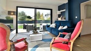 Ein modernes Wohnzimmer mit einem blauen Sofa, roten Sessel und einem weißen Couchtisch.