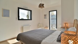 Ein Schlafzimmer mit Bett, Fenster, Heizkörper und Lampe.