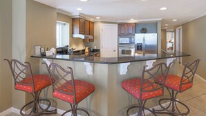 Una cocina con isla central, electrodomésticos de acero inoxidable y sillas rojas con estampado.