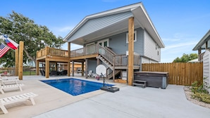 A two-story house with a backyard pool, a basketball hoop, and a covered patio area.