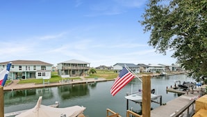 A marina with docked boats, a river, and residential buildings in the background.