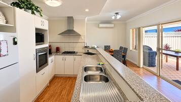 A modern kitchen with stainless steel appliances, a built-in oven, and a large island with a sink.