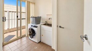 A laundry room with a washing machine, a drying rack, and a sink.