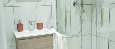 A modern bathroom with a glass-enclosed shower, a wooden vanity with a white sink, and a mirror above the vanity.