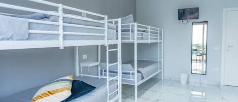 A bunk bed room with a television mounted on the wall and a door leading to an outdoor area.