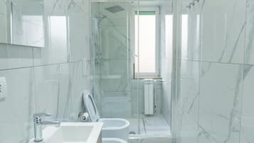 Un baño moderno con ducha acristalada, lavabo e inodoro.