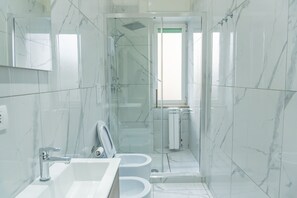 A modern bathroom with a glass-enclosed shower, a sink, and a toilet.
