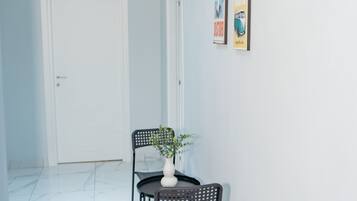 Ein Korridor mit einer weißen Tür, einem kleinen Tisch mit Stühlen und zwei gerahmten Bildern an der Wand.