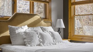 A neatly made bed with white linens and decorative pillows, a wooden headboard, and a bedside lamp. - Ski Side Retreat: Soak, Ski, Sip (Telluride)