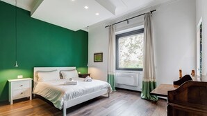A bedroom with a bed, bedside tables, a window with curtains, and a view of greenery outside. - Music Bridge Apartment (Roma)