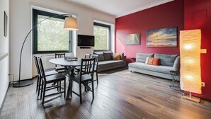 A modern living room with a dining area, red walls, and a large window. - Music Bridge Apartment (Roma)