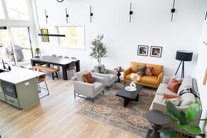 A modern living room with a dining area, a sofa set, a coffee table, and a potted plant.