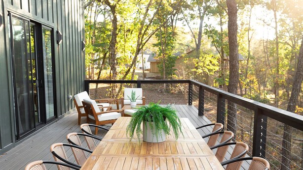 Eine Holzterrasse mit Esstisch und Stühlen, umgeben von Bäumen.
