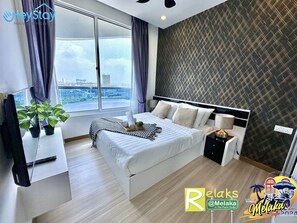 A modern hotel room with a large bed, a small bedside table, a potted plant, and a view of the city through a large window. - The Wave Residence (Malacca City)
