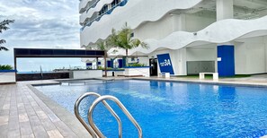 A modern hotel pool area with a clear view of the sea, a wavy architectural design, and a sign indicating 'Tower A Level 3A'. - The Wave Residence (Malacca City)
