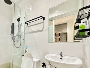 A modern bathroom with a glass-enclosed shower, a white sink, and a mirror with a wooden frame. - The Wave Residence (Malacca City)
