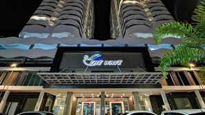 Un hôtel reconnaissable à son grand panneau « The Wave », qui présente une architecture moderne avec deux bâtiments imposants et une structure ondulée à l’entrée.