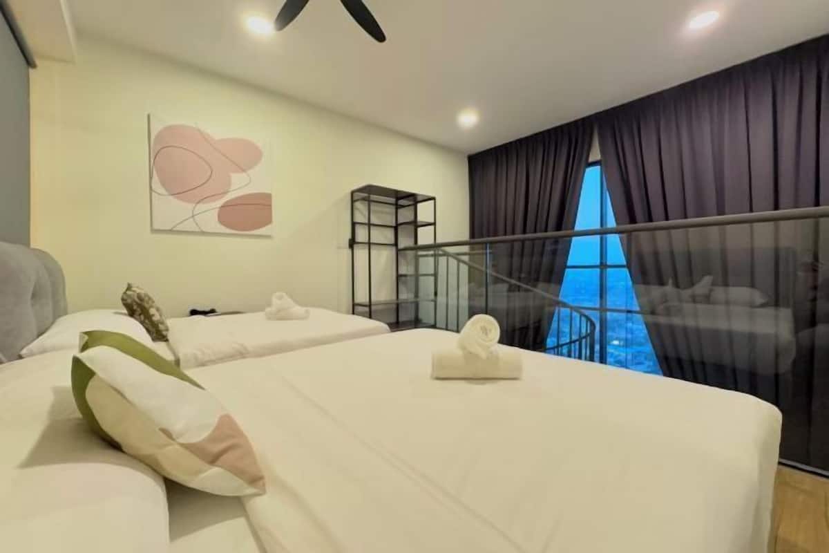 A hotel room with two beds, a glass partition, a view of the city, and a modern art piece on the wall.