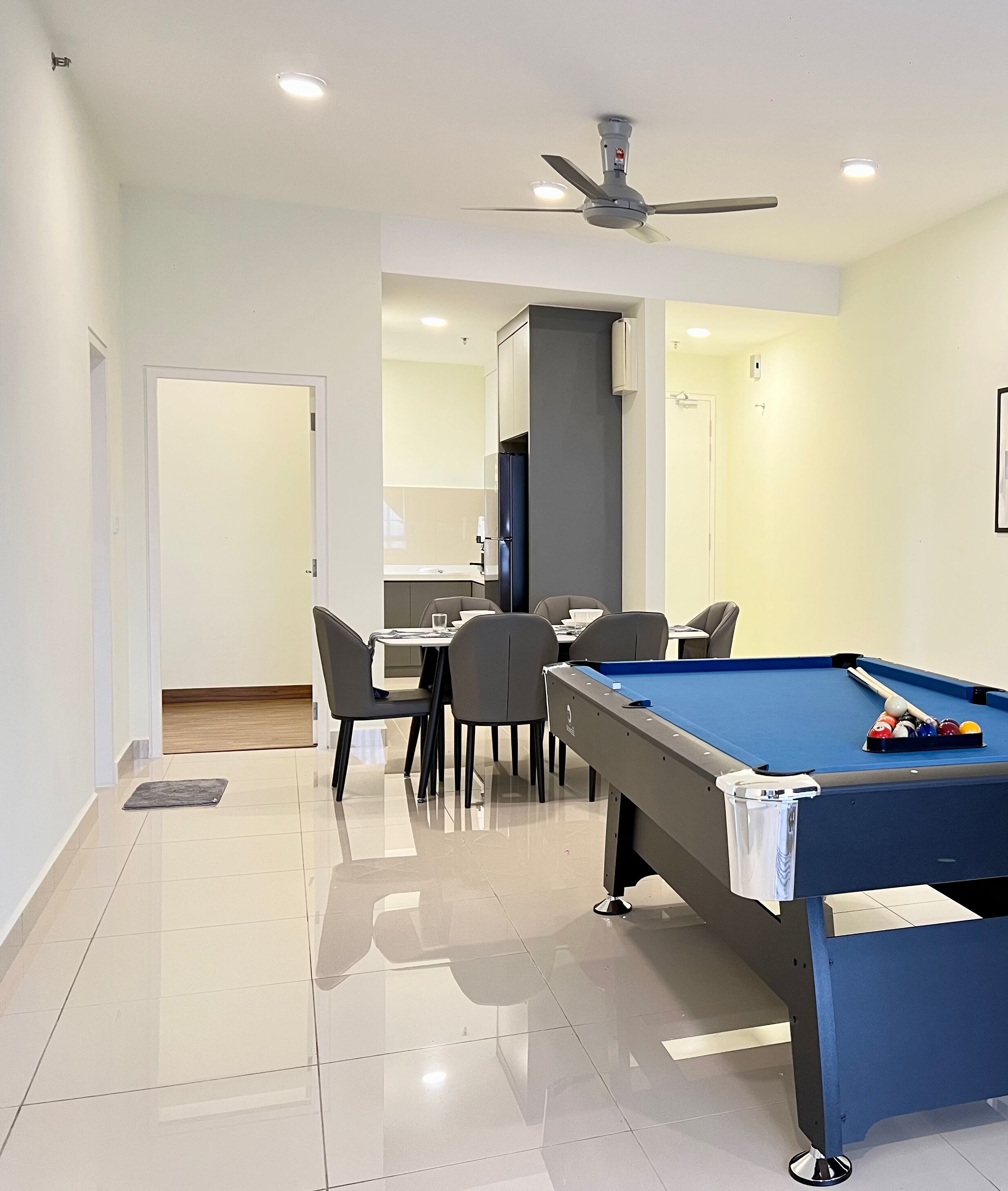 Une pièce moderne équipée d’une table de billard, d’un ventilateur de plafond et d’un coin repas avec des chaises et une table.