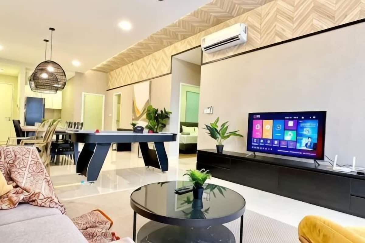 A modern living room with a pool table, a flat-screen TV, and a dining area.