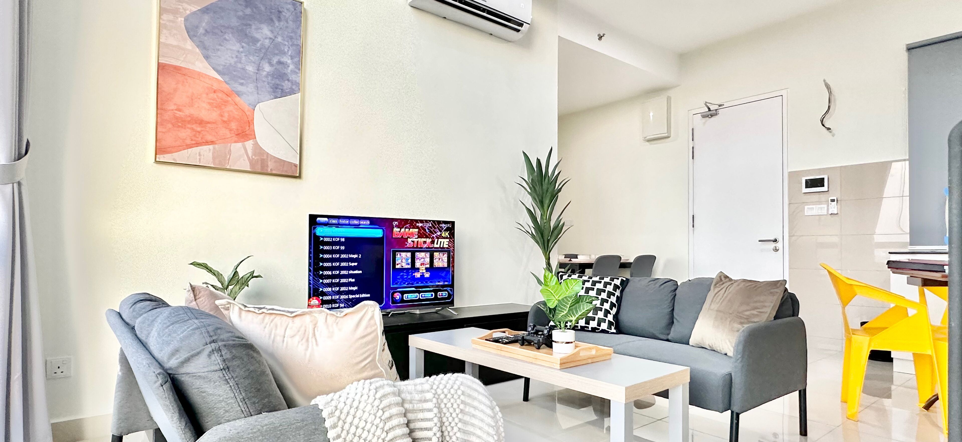 A modern living room with a grey sofa, a coffee table, and a TV displaying a video game.