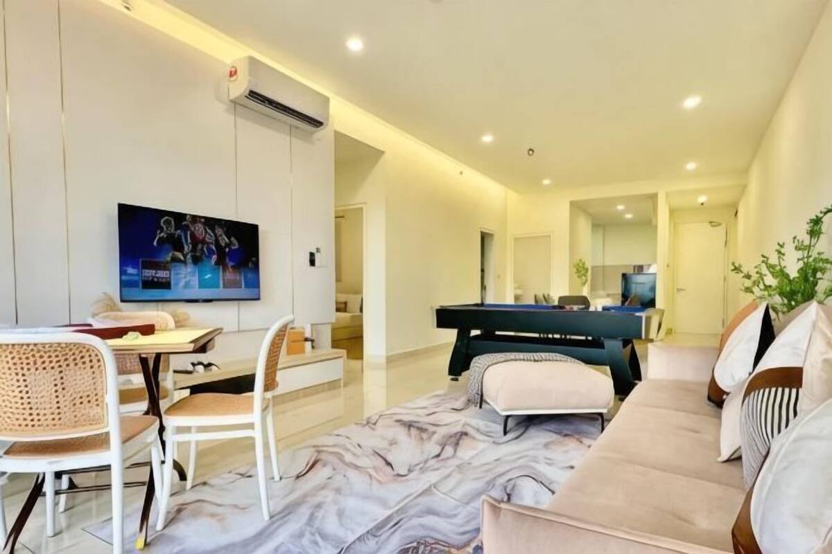 A modern living room with a sofa, a dining table, a TV, and a pool table.