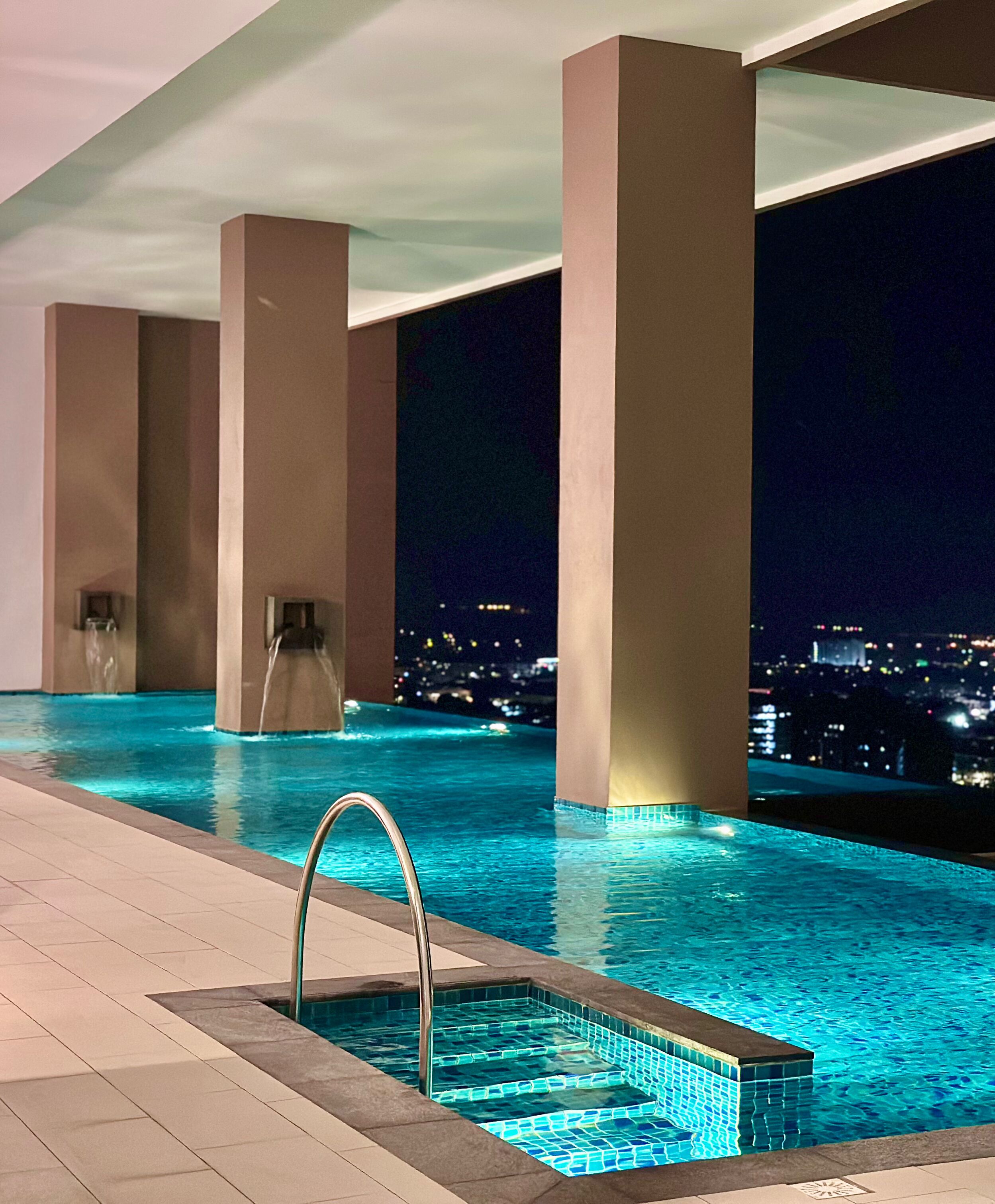 A modern indoor swimming pool with a city view at night.