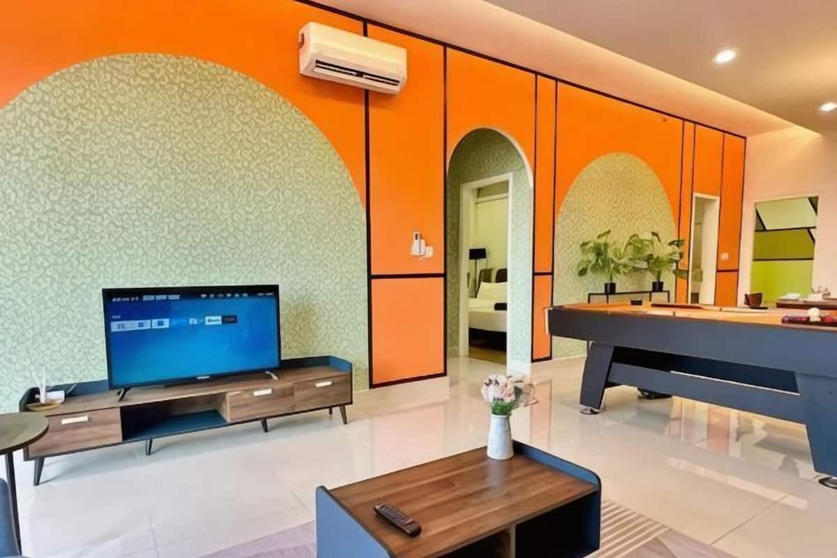 A modern hotel lobby with a large flat-screen TV, a reception desk, and a seating area with a coffee table.