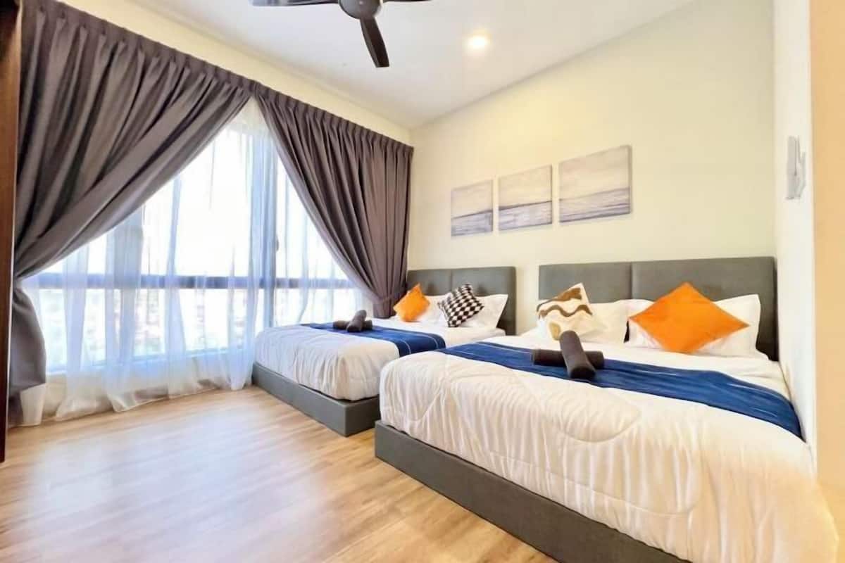A hotel room with two beds, a ceiling fan, and a large window with curtains.